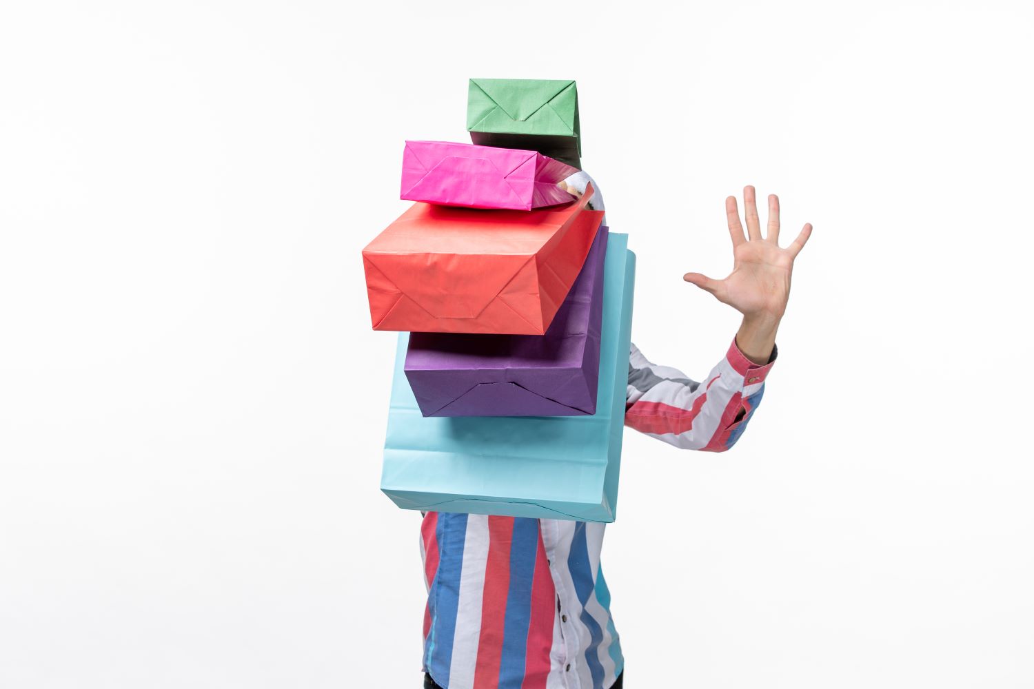 Hombre cargando con demasiados paquetes de colores que le tapan la visión, metáfora de estar sobrepasado por las demandas de los demás.