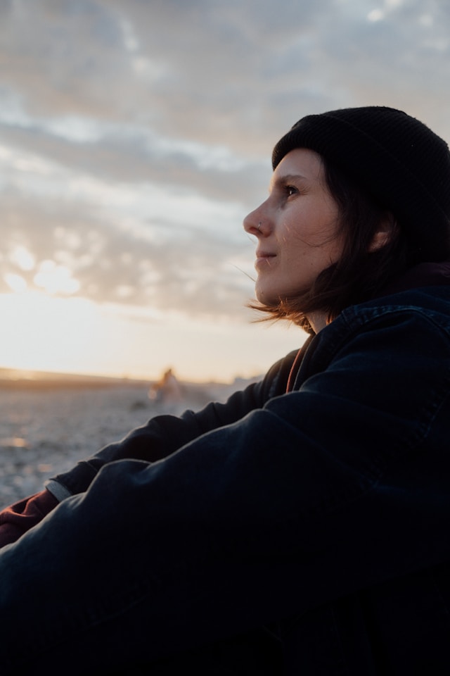 Mujer sentada contemplando el horizonte al atardecer.