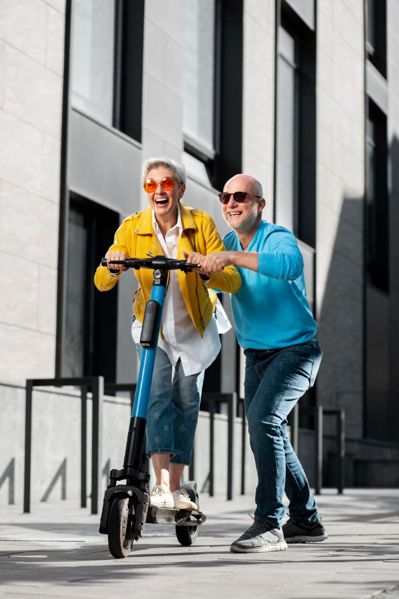 Mujer y hombre maduros divirtiéndose con un patinete eléctrico